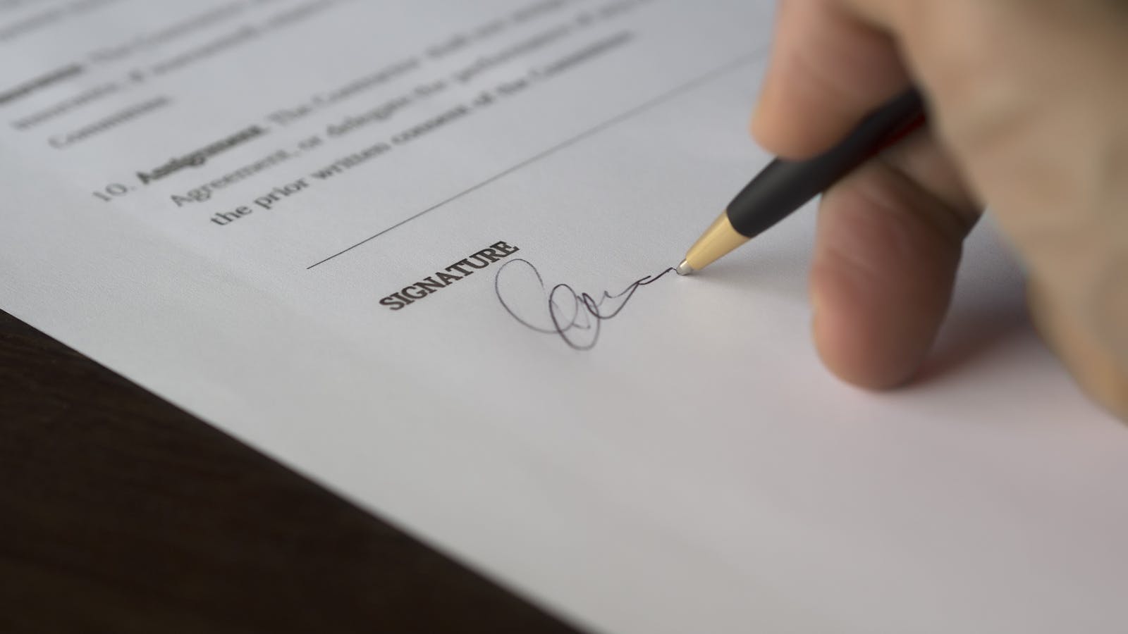 A service contractor signing employment paperwork at a desk with a calculator, employment forms, and a coffee - capturing the moment of formalizing a first hire.